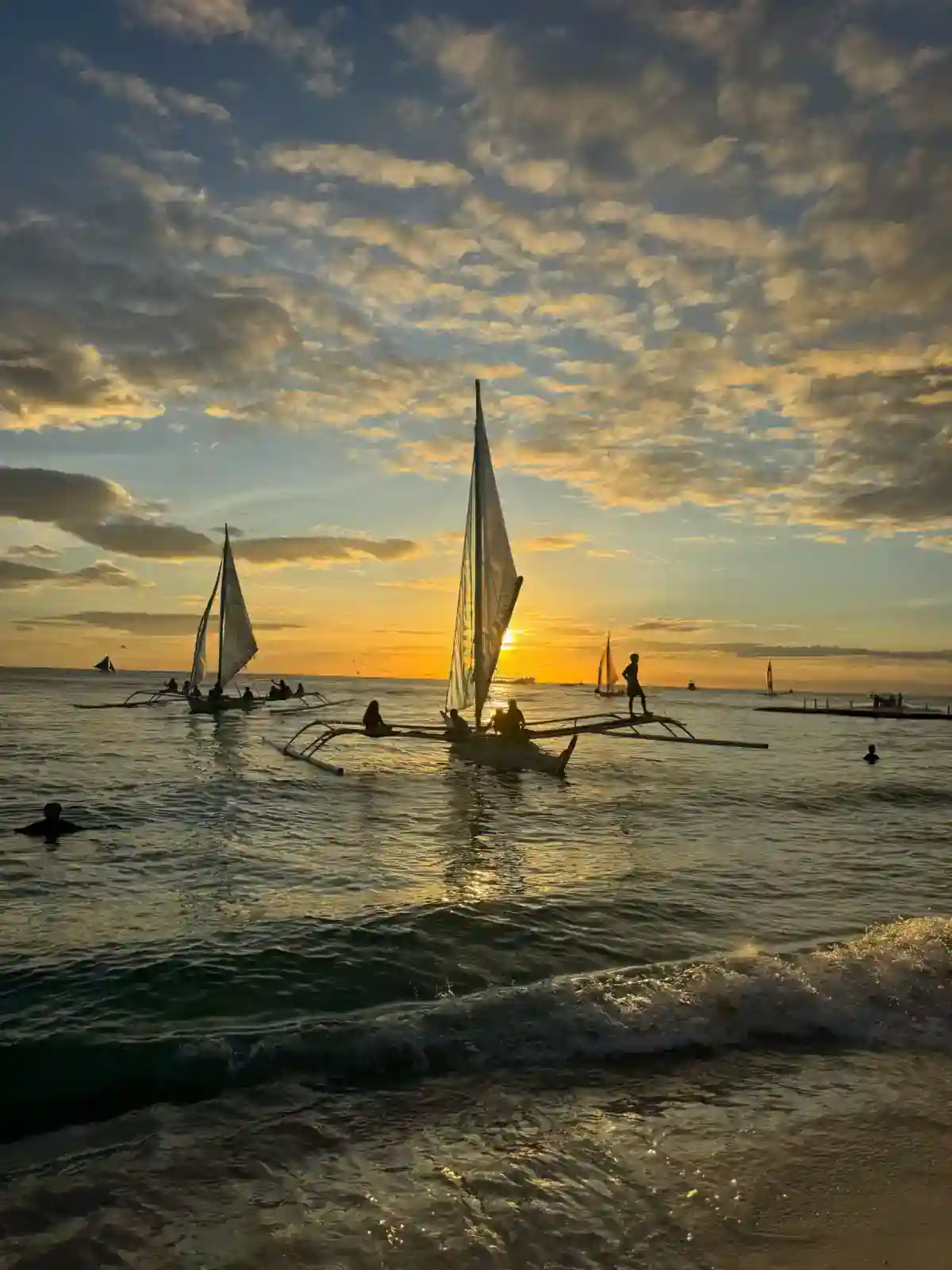 Traditional paraw sailing boats off White Beach, Boracay, at sunset